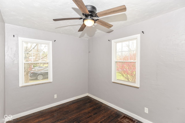 spare room featuring ceiling fan, a healthy amount of sunlight, and dark hardwood / wood-style flooring