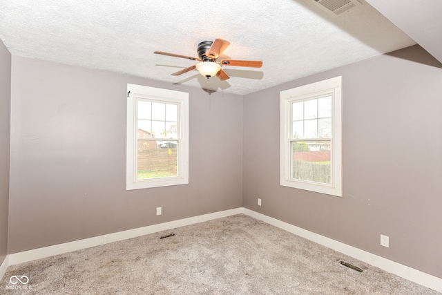 carpeted empty room featuring a wealth of natural light, ceiling fan, and a textured ceiling