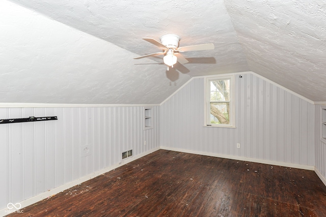 additional living space with a textured ceiling, dark hardwood / wood-style flooring, and lofted ceiling