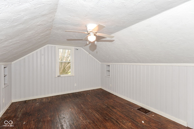 bonus room featuring wood walls, lofted ceiling, ceiling fan, a textured ceiling, and wood-type flooring