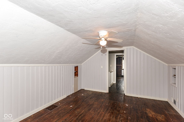 bonus room featuring a textured ceiling, ceiling fan, dark hardwood / wood-style flooring, and vaulted ceiling