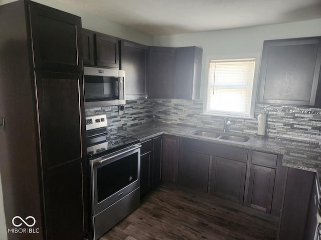 306 E Cherry St, Advance, IN 46102 - kitchen with stainless steel appliances, a sink, tasteful backsplash, dark wood finished floors, and dark stone counters