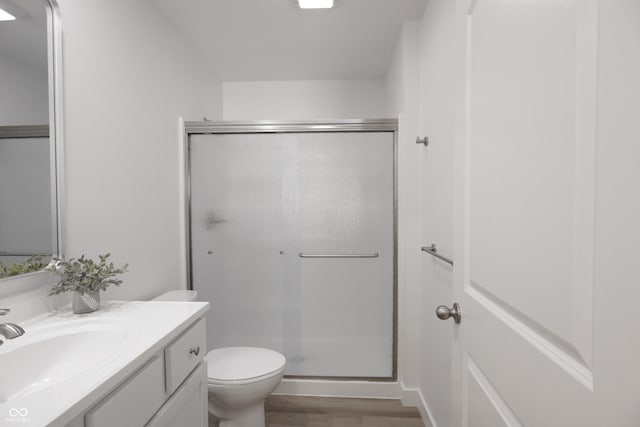 bathroom with walk in shower, hardwood / wood-style floors, vanity, and toilet