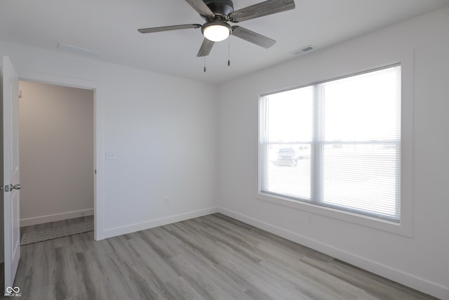 empty room with ceiling fan, light hardwood / wood-style flooring, and a healthy amount of sunlight