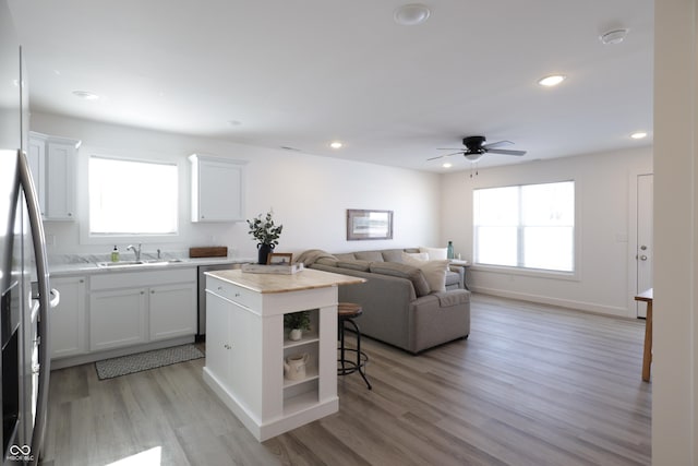 kitchen with white cabinetry, a center island, and sink