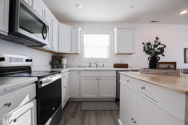 kitchen featuring dark wood-type flooring, sink, white cabinetry, wooden counters, and appliances with stainless steel finishes