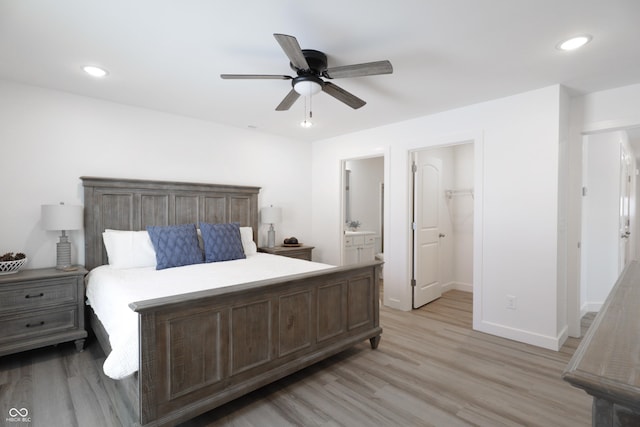 bedroom featuring ensuite bath, light hardwood / wood-style flooring, ceiling fan, a walk in closet, and a closet