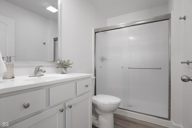 bathroom featuring vanity, hardwood / wood-style flooring, a shower with door, and toilet