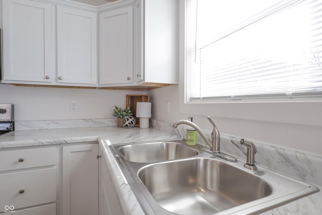 kitchen featuring white cabinetry, sink, and light stone counters