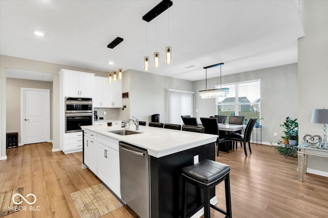 kitchen featuring decorative light fixtures, white cabinetry, a kitchen island with sink, and stainless steel appliances