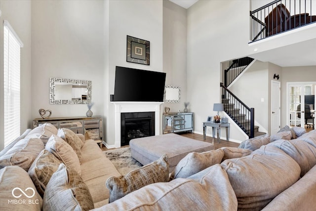 living room featuring hardwood / wood-style floors, a towering ceiling, and a healthy amount of sunlight