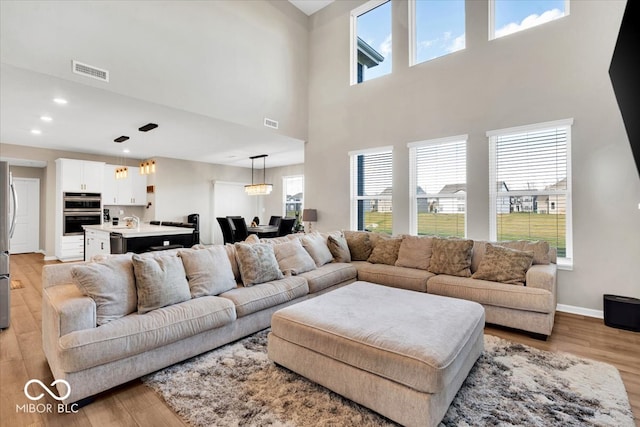 living room with a towering ceiling and light wood-type flooring