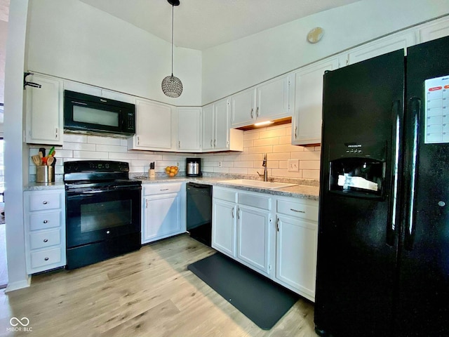 kitchen featuring sink, hanging light fixtures, white cabinets, black appliances, and light wood-type flooring