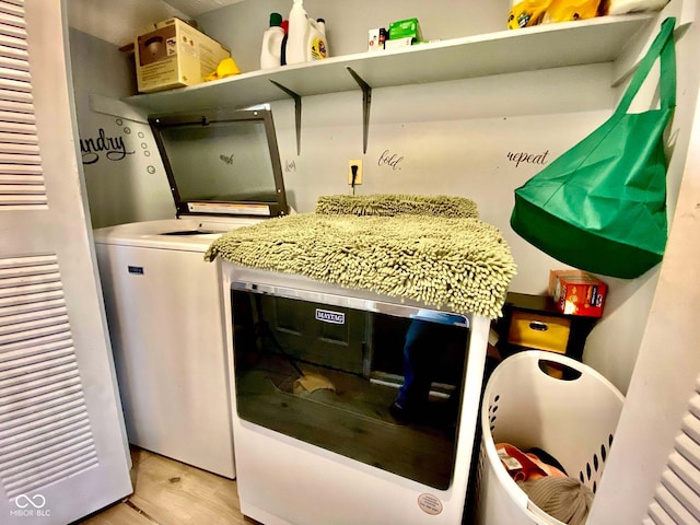 clothes washing area with washing machine and dryer and light wood-type flooring