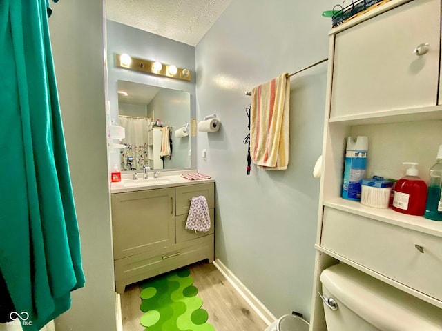 bathroom with vanity, hardwood / wood-style floors, a textured ceiling, and toilet