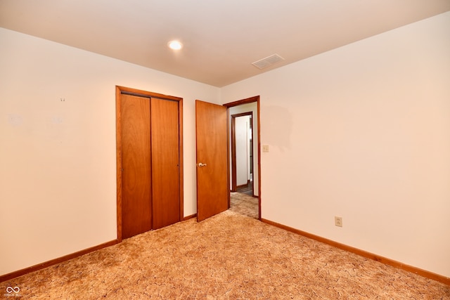 unfurnished bedroom with light colored carpet and a closet