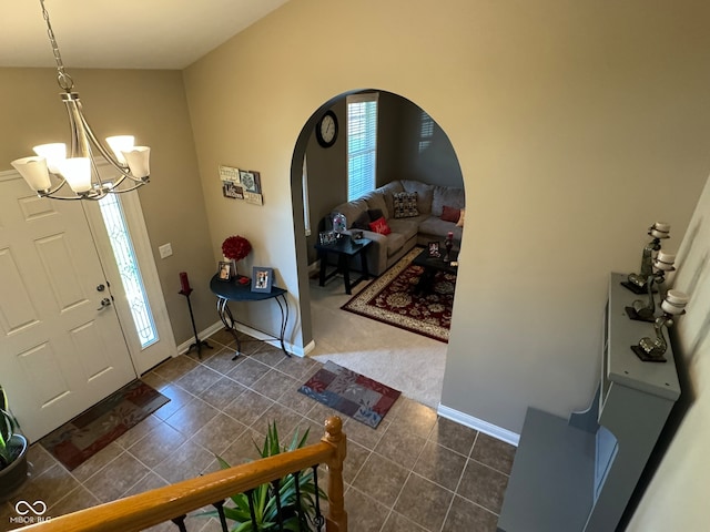 tiled foyer entrance featuring a chandelier and vaulted ceiling