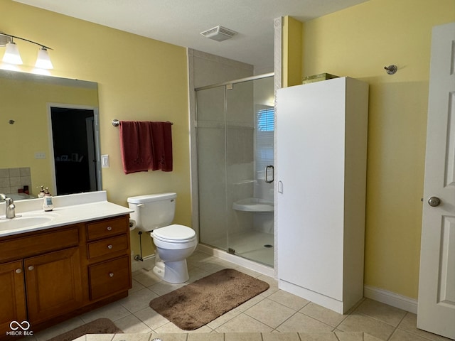 bathroom featuring toilet, vanity, tile patterned floors, and a shower with shower door