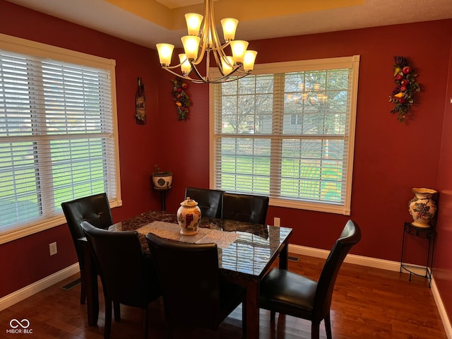 dining area featuring dark wood-type flooring and an inviting chandelier