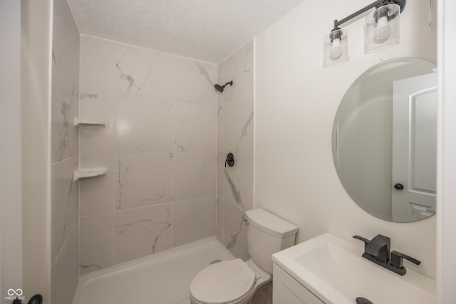 bathroom with a tile shower, vanity, a textured ceiling, and toilet