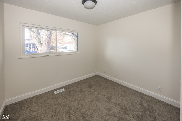 empty room with a textured ceiling and dark carpet