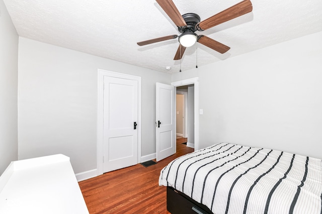 bedroom featuring ceiling fan, dark wood-type flooring, and a textured ceiling