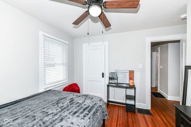 bedroom with dark hardwood / wood-style floors, ceiling fan, and a textured ceiling