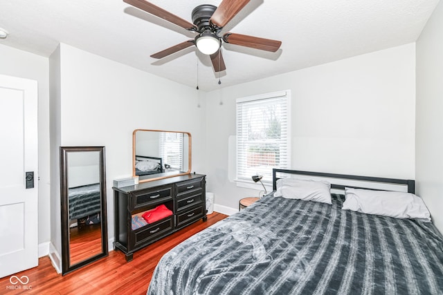 bedroom with hardwood / wood-style floors, ceiling fan, and a textured ceiling