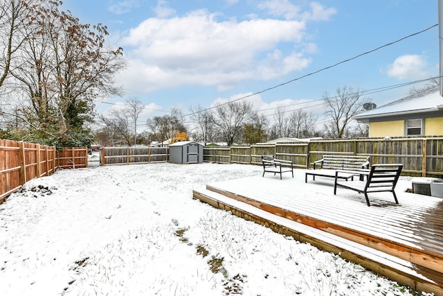 snowy yard featuring a storage shed and a wooden deck