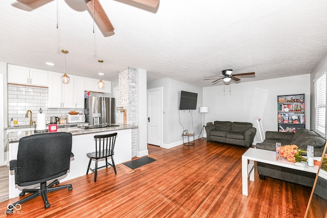 living room featuring ceiling fan, sink, wood-type flooring, and a textured ceiling