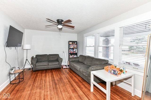 living room with a textured ceiling, ceiling fan, and dark wood-type flooring