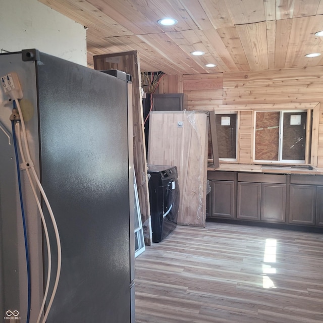 kitchen featuring stainless steel refrigerator, wooden ceiling, independent washer and dryer, wood walls, and light wood-type flooring