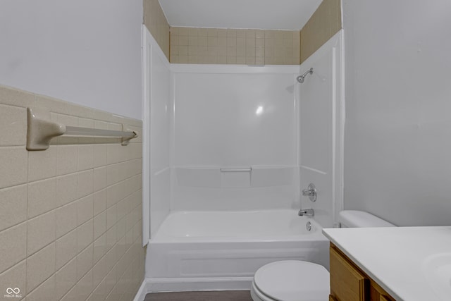 full bathroom featuring  shower combination, vanity, tile walls, and toilet