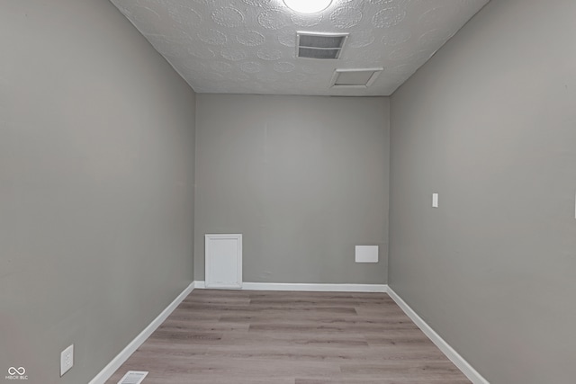 unfurnished room with light wood-type flooring and a textured ceiling