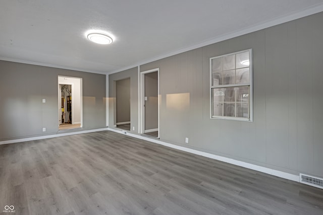 spare room featuring wood-type flooring and ornamental molding