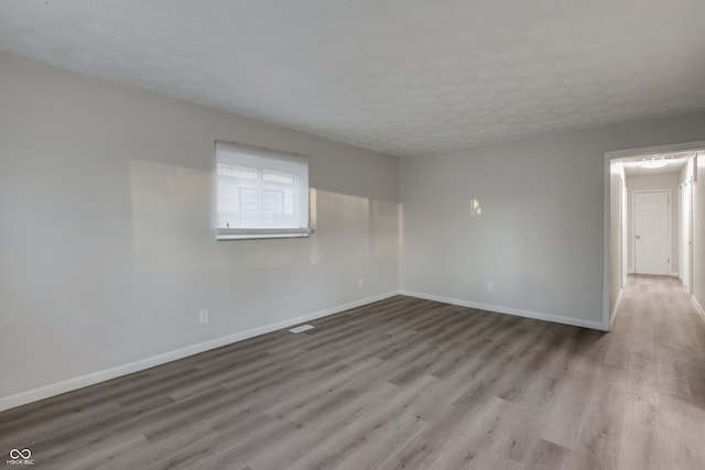 empty room featuring a textured ceiling and light hardwood / wood-style flooring