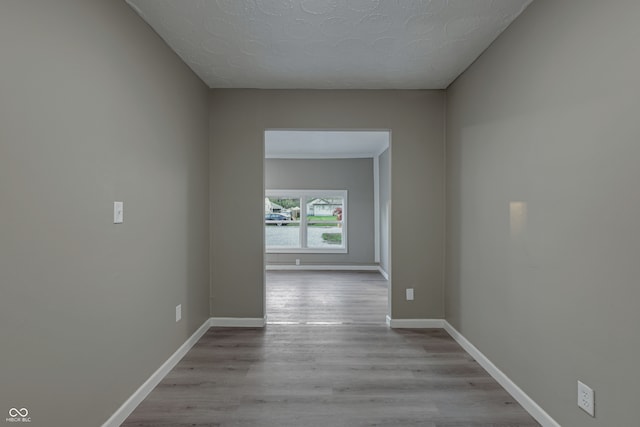 hallway with light hardwood / wood-style floors and a textured ceiling