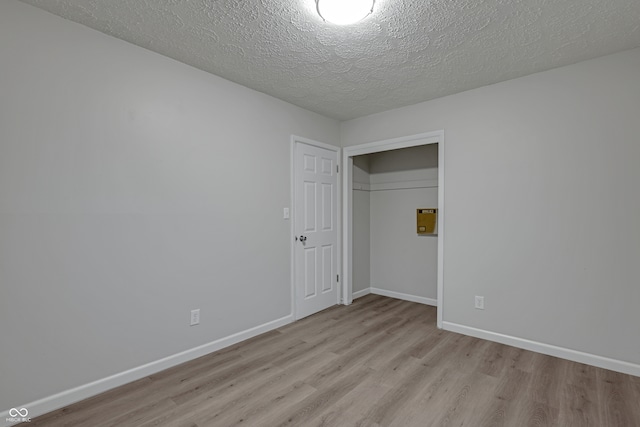 unfurnished room with a textured ceiling and light hardwood / wood-style flooring