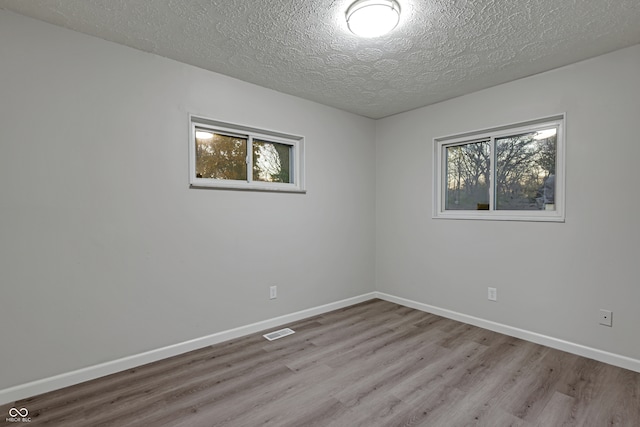 spare room featuring a textured ceiling and light wood-type flooring