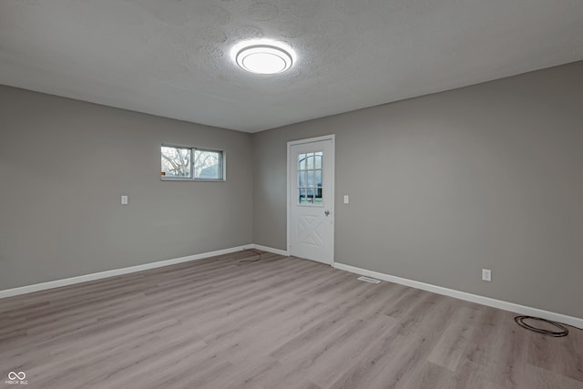 unfurnished room featuring a textured ceiling and light hardwood / wood-style floors