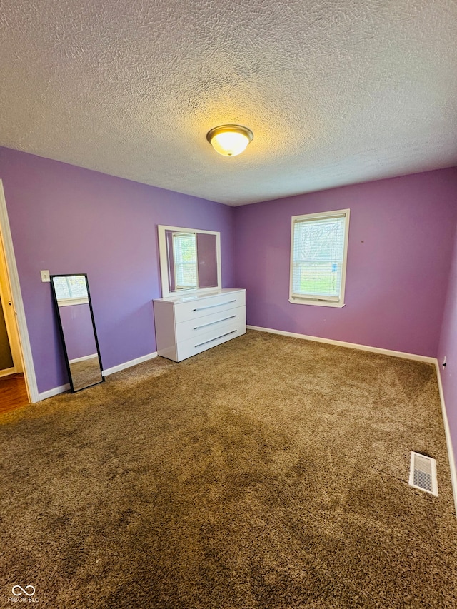 unfurnished bedroom featuring a textured ceiling, carpet floors, and multiple windows