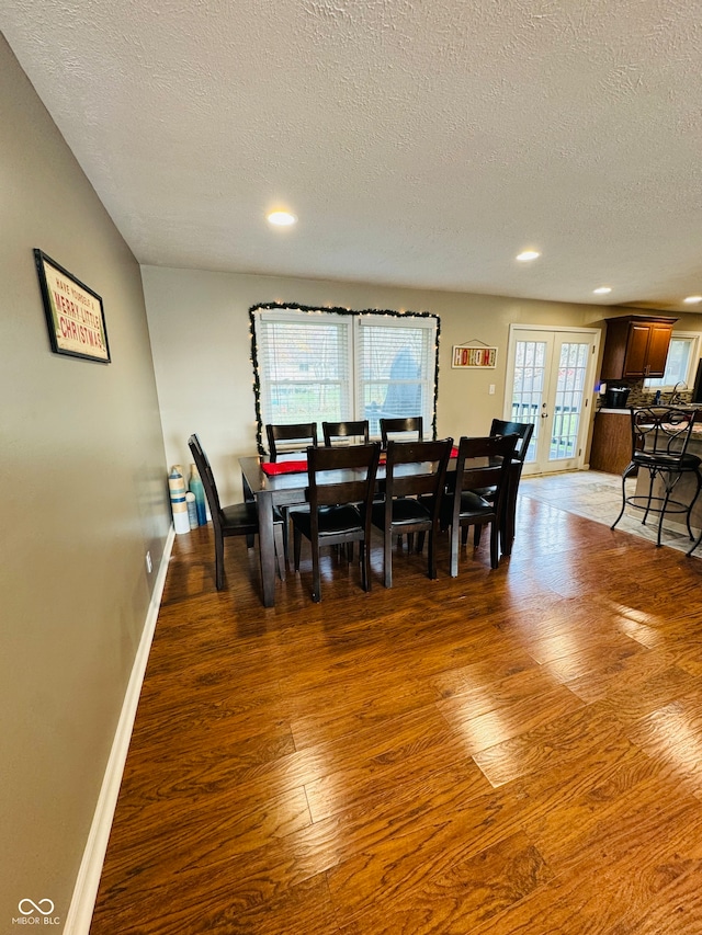 dining area featuring a textured ceiling, dark wood-type flooring, and french doors