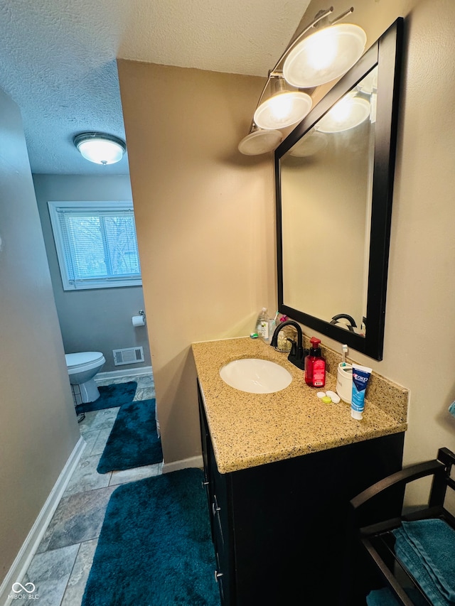 bathroom with tile patterned flooring, vanity, a textured ceiling, and toilet