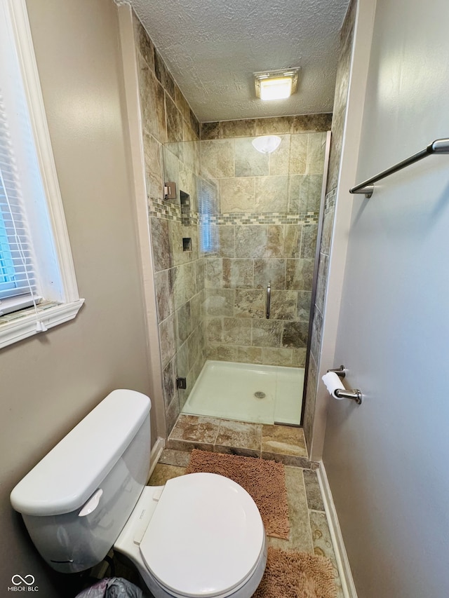 bathroom with a textured ceiling, toilet, and walk in shower