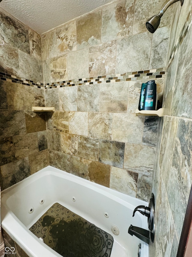 bathroom featuring a textured ceiling and tiled shower / bath