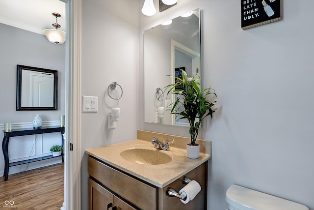 bathroom featuring crown molding, vanity, wood-type flooring, and toilet