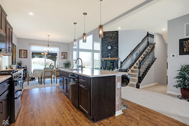 kitchen with gas range, dark brown cabinetry, sink, hardwood / wood-style floors, and an island with sink