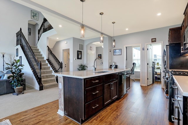 kitchen featuring sink, stainless steel appliances, pendant lighting, a kitchen island with sink, and dark brown cabinets