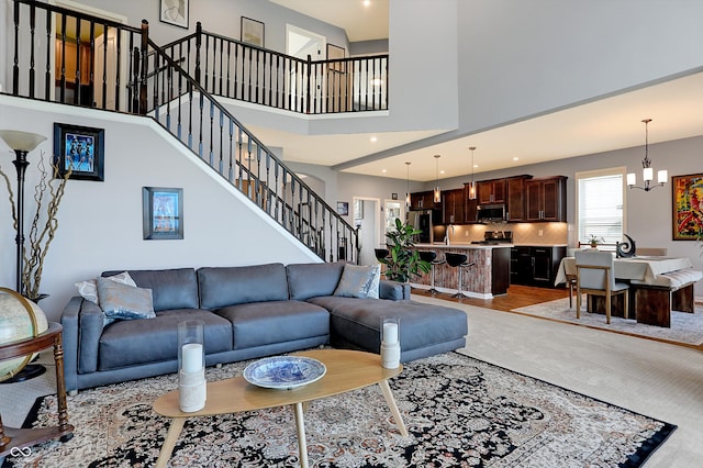 living room featuring light hardwood / wood-style flooring, a towering ceiling, and a chandelier