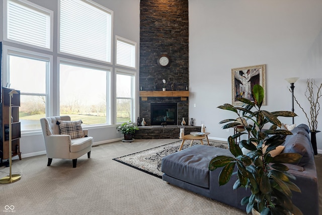 living room with a stone fireplace, carpet floors, and a high ceiling